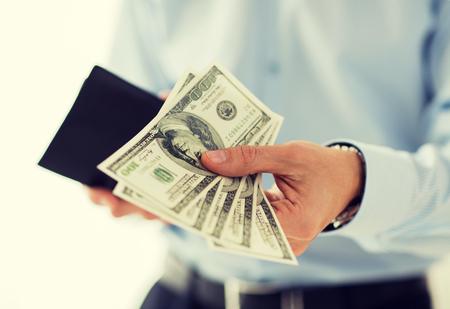 people, business, finances and money concept - close up of businessman hands holding open wallet with dollar cashの写真素材
