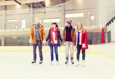 people, friendship, sport and leisure concept - happy friends on skating rinkの写真素材