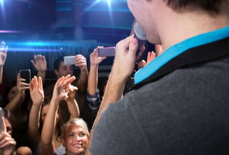 holidays, music, nightlife and people concept - close up of singer singing on stage over happy...