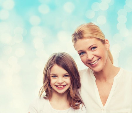 family, childhood, happiness and people - smiling mother and little girl over blue lights backgroundの写真素材