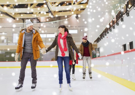 people, friendship, sport and leisure concept - happy friends on skating rinkの写真素材