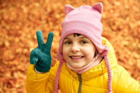 autumn, childhood, nature and people concept - happy little girl over fallen leaves in park