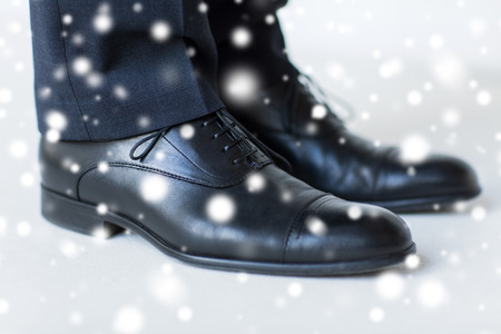 people, business, fashion and footwear concept - close up of man legs in elegant shoes with laces or lace boots over snow effect over snow effectの写真素材