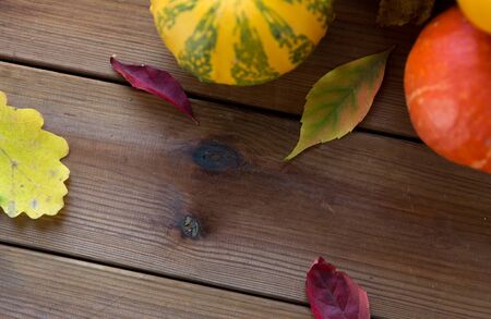 harvest, season, advertisement and autumn concept - close up of pumpkins and leaves on wooden table...