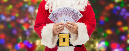 christmas, holidays, winning, currency and people concept - close up of santa claus with euro money over lights backgroundの写真素材