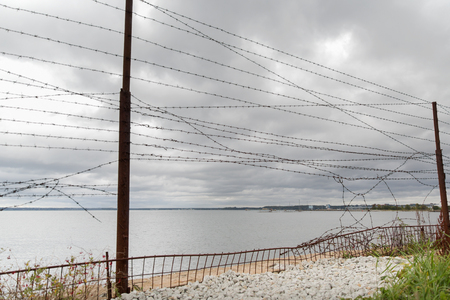 imprisonment, restriction concept - barb wire fence over gray sky and sea imprisonment, restriction concept - barb wire fence over gray sky and sea