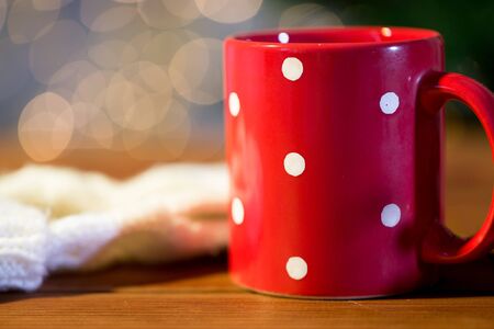 holidays, christmas, winter and drinks concept - red polka dot tea cup on wooden tableの写真素材