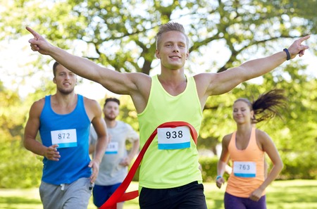 fitness, sport, victory, success and healthy lifestyle concept - happy man winning race and coming...