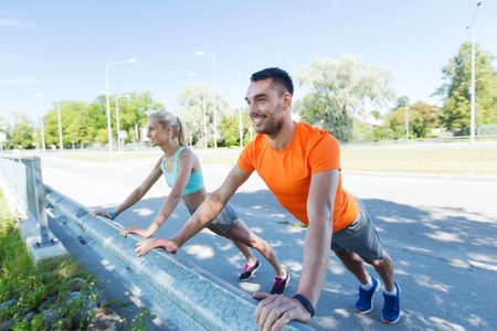 fitness, sport, training and healthy lifestyle concept - close up of happy couple doing push-ups outdoorsの写真素材