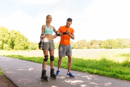 fitness, sport, summer and healthy lifestyle concept - happy couple with roller skates riding...