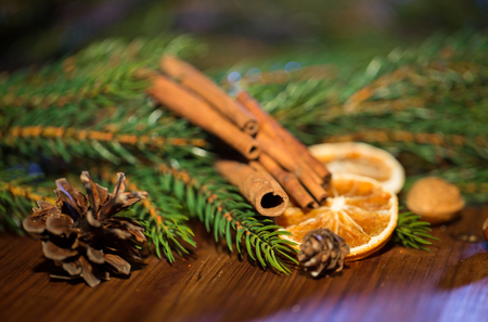 decoration, winter, holidays and new year concept - close up of christmas fir branch with cinnamon and dried orange on wooden tableの写真素材