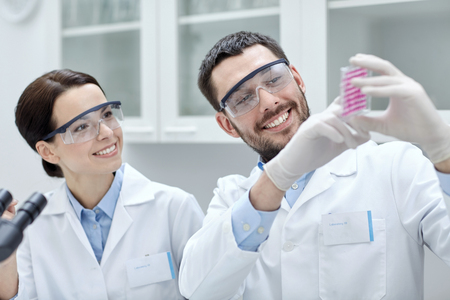 science, chemistry, biology, pharmacy and people concept - young scientists with pipette and flask making test or research in clinical laboratoryの写真素材