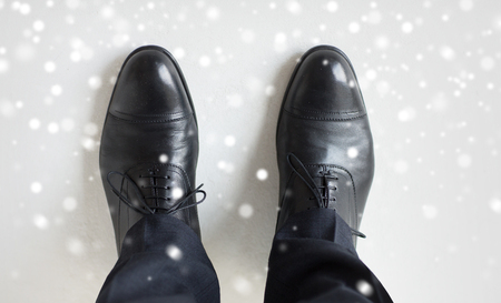 people, business, fashion and footwear concept - close up of man legs in elegant shoes with laces or lace boots over snow effectの写真素材