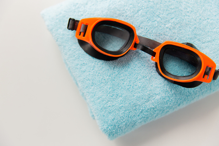 sport, fitness, water sports and objects concept - close up of swimming goggles and towelの写真素材
