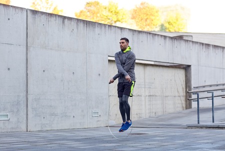 fitness, sport, people, exercising and lifestyle concept - man skipping with jump rope outdoors