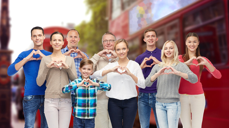 gesture, travel, tourism and people concept -  happy family  showing heart shape hand sign over london city street backgroundの写真素材