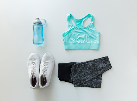 sport, fitness, healthy lifestyle and objects concept - close up of female sports clothing and...