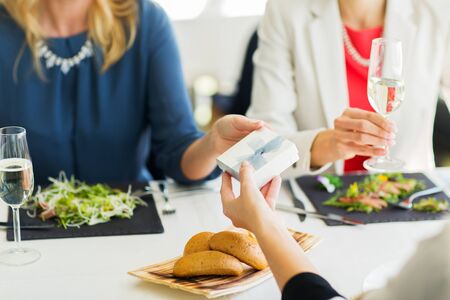 people, holidays, celebration and lifestyle concept - close up of women giving birthday present at...