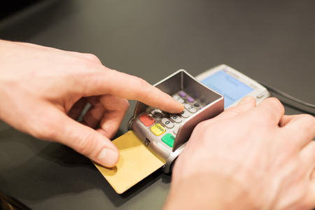 finance, technology, payment , money and people concept - close up of hand entering pin code to bank...