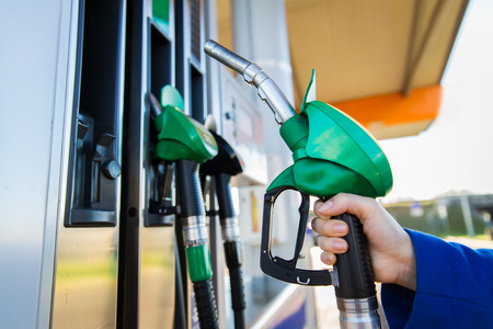object, fuel, oil, tank and transport concept - close up of hand holding gasoline hose at gas...