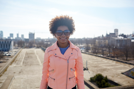 tourism, travel, people, international  and leisure concept - happy african american teenage girl or young woman in shades on tallinn city streetの写真素材