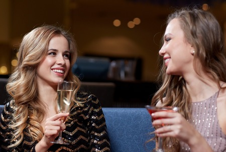 celebration, friends, bachelorette party and holidays concept - happy women drinking champagne and cocktails at night clubの写真素材