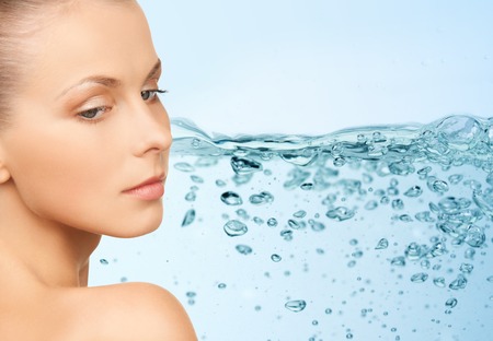 beauty, people, moisturizing, body care and health concept - young woman face with bare shoulders over water splash backgroundの写真素材
