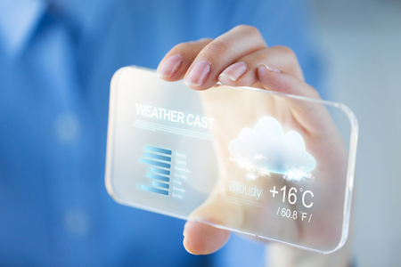 technology, forecast and people concept - close up of woman hand holding and showing weather cast on transparent smartphoneの写真素材