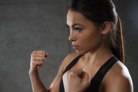 sport, fitness, martial arts and people concept - woman holding fists and fighting in gymの写真素材