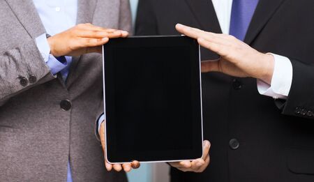 business, technology, internet and office concept - businessman and businesswoman with blank black tablet pc screen in officeの写真素材
