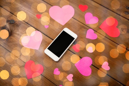 advertisement, romance, valentines day and holidays concept - close up of smartphone and hearts on...