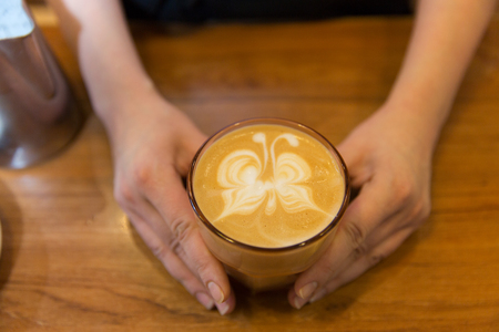 equipment, coffee shop, people and technology concept - close up of hands with latte art etching in coffee cupの写真素材