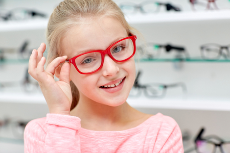 health care, people, eyesight and vision concept - little girl in glasses at optics storeの写真素材