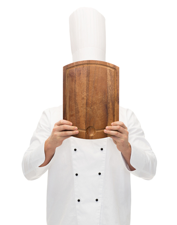 cooking, profession and people concept - male chef cook covering face or hiding behind wooden cutting boardの写真素材