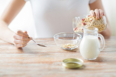 food, healthy eating, people and diet concept - close up of woman eating muesli with milk for breakfastの写真素材
