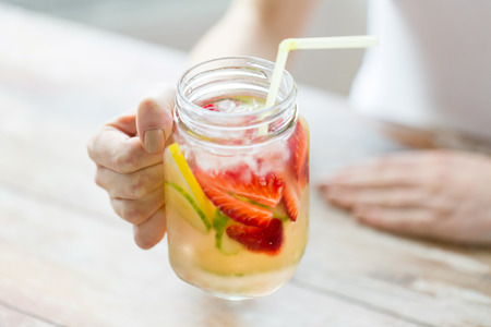 healthy eating, drinks, diet, detox and people concept - close up of happy woman holding glass with...