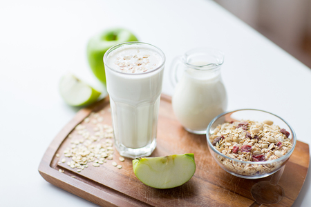 food, healthy eating and diet concept - close up of muesli, milk jug and yogurt in glass on cutting boardの写真素材
