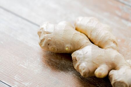 ethno science, culinary, diet, eco food and objects concept - close up of ginger root on wooden tableの写真素材