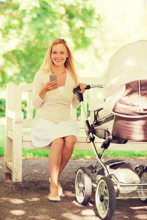 family, parenthood, technology and people concept - happy mother with with smartphone and baby...