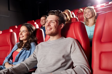cinema, entertainment and people concept - happy friends watching movie in theaterの写真素材