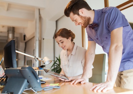 business, startup and people concept - happy creative team with tablet pc computer in officeの写真素材