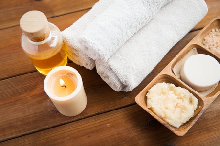 beauty, spa, body care, natural cosmetics and wellness concept - close up of soap with candle and bath towels on wooden tableの写真素材