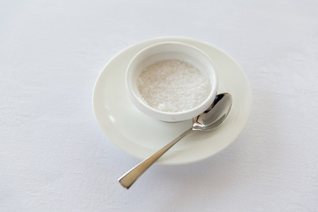 sweetener, carbohydrates, diet and unhealthy eating - sugar bowl and saucer with spoon on tableの写真素材