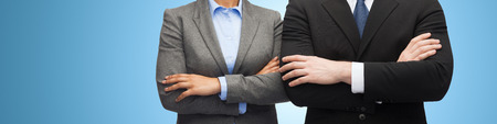 business, people, cooperation and education concept - close up of businesswoman and businessman with crossed arms over blue backgroundの写真素材