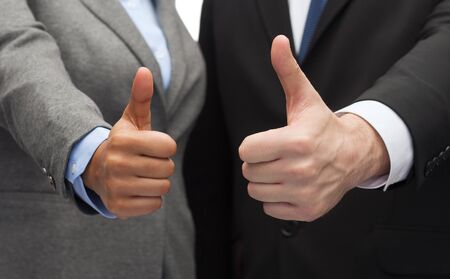 business and office concept - businessman and businesswoman showing thumbs upの写真素材