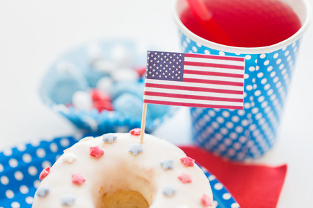 american independence day, celebration, patriotism and holidays concept - close up of glazed sweet donut with juice and candies in disposable tableware at 4th july partyの写真素材