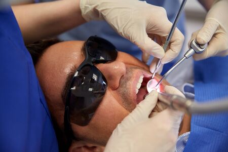 people, medicine, stomatology and health care concept - close up of dentist and assistant hands with...