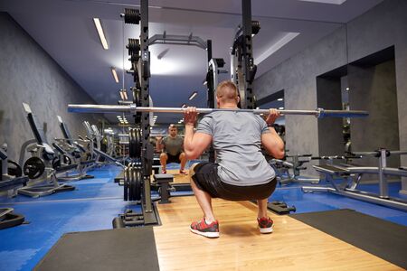 sport, fitness, bodybuilding, lifestyle and people concept - young man with bar flexing muscles in...