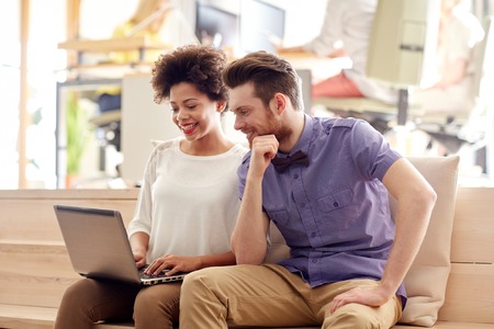 business, startup and people concept - happy creative team with laptop computer in officeの写真素材