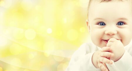 people, children and babyhood concept - close up of of happy baby over yellow background